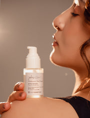 Woman holding a bottle of skincare serum with a blurred background